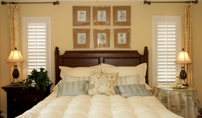 Tall plantation shutters framing bed in a bedroom in Washington DC 